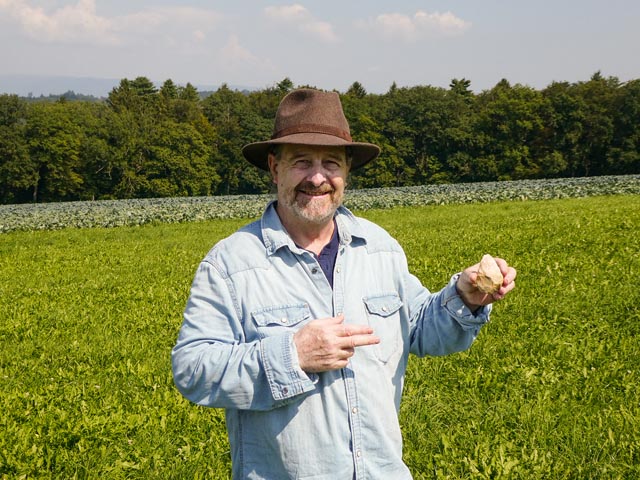 Der Finder Georges Sprecher mit dem neu entdeckten Faustkeil von Füllinsdorf. Foto: Archäologie Baselland. 